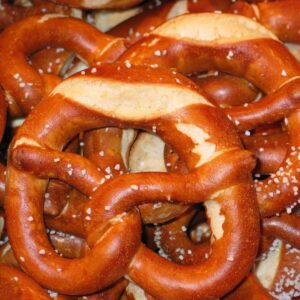 Authentic German soft pretzels with a golden-brown crust, sprinkled with coarse salt, placed on a wooden surface.