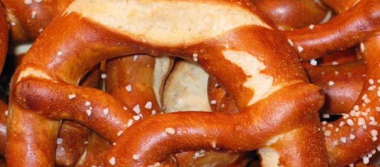 Authentic German soft pretzels with a golden-brown crust, sprinkled with coarse salt, placed on a wooden surface.