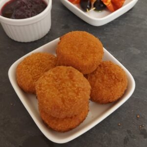 Golden brown baked Camembert bites served with a side of lingonberry sauce.