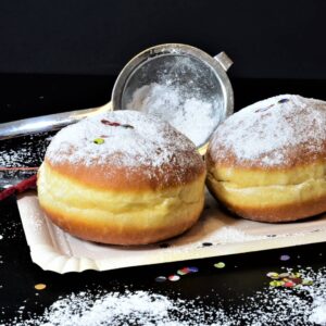 Two homemade Berliner Pfannkuchen dusted with powdered sugar.