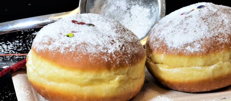 Two homemade Berliner Pfannkuchen dusted with powdered sugar.