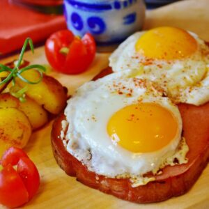 A slice of Leberkase topped with a perfectly fried egg, served with fresh parsley garnish.