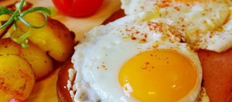 A slice of Leberkase topped with a perfectly fried egg, served with fresh parsley garnish.