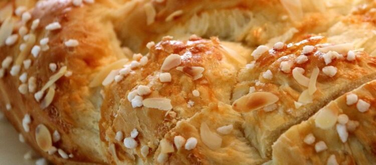 Close-up of a freshly baked Hefezopf topped with sugar crystals and almond slices.