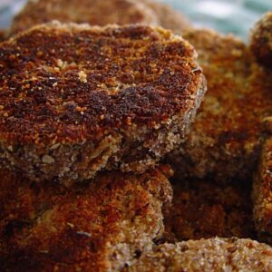 Close-up of freshly fried Berliner Bouletten with a golden-brown crust, served on a plate with mustard and fresh parsley.